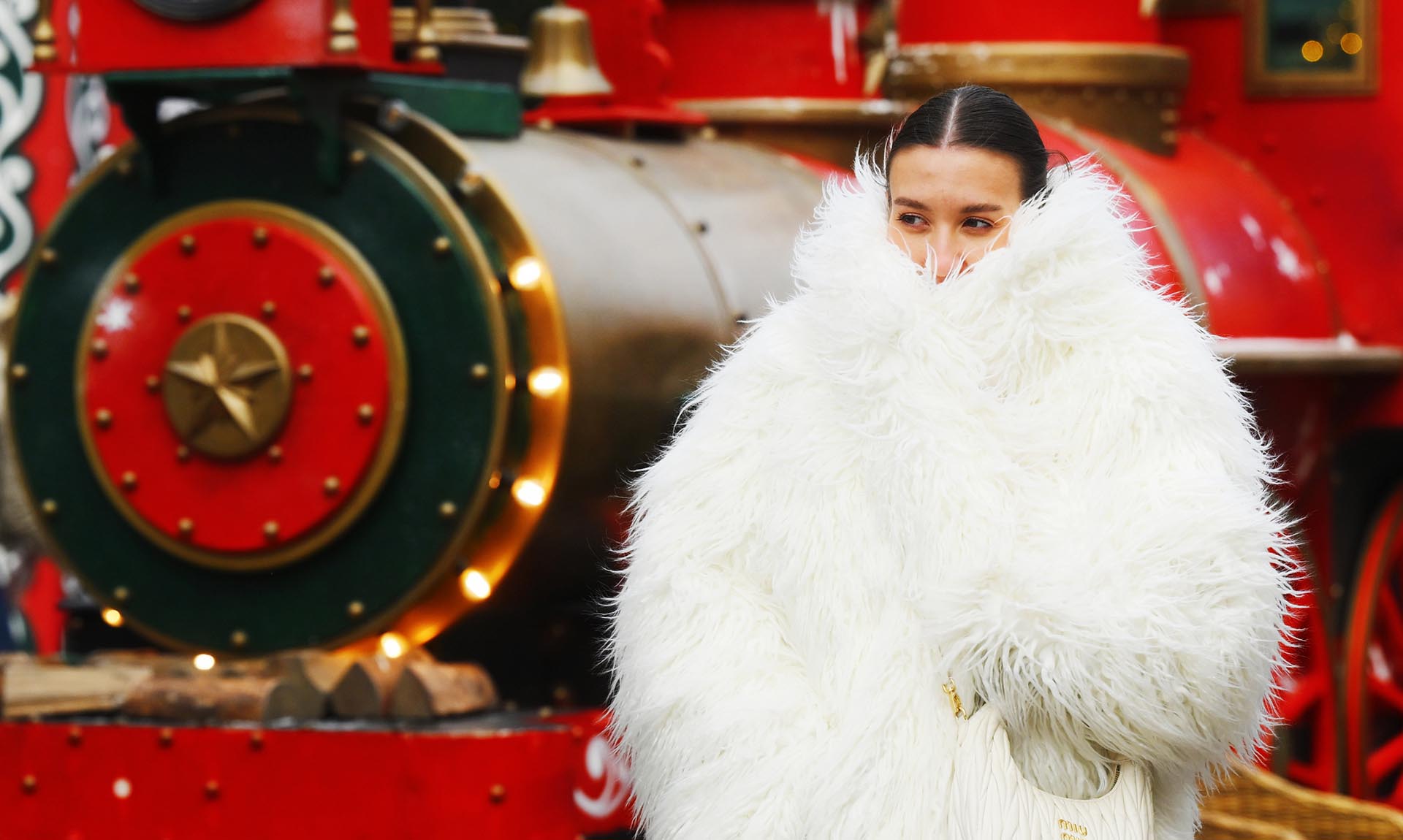 Девушка в шубе возле рождественского поезда
