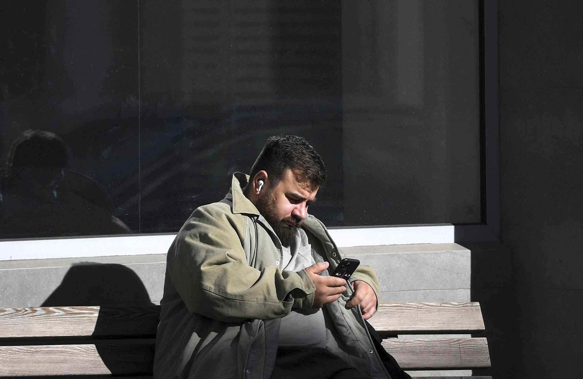 мужчина со смартфоном в руках на лавочке