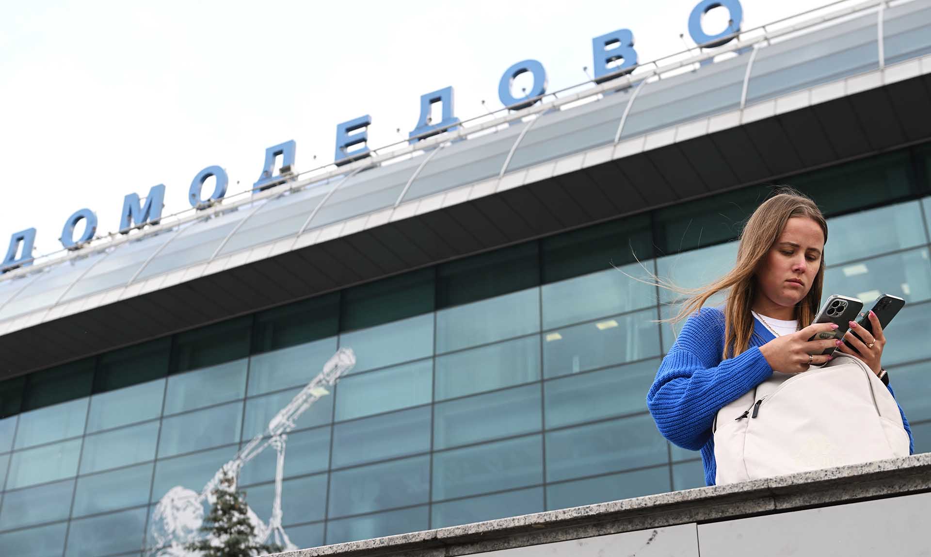 Девушка с телефоном около аэропорта