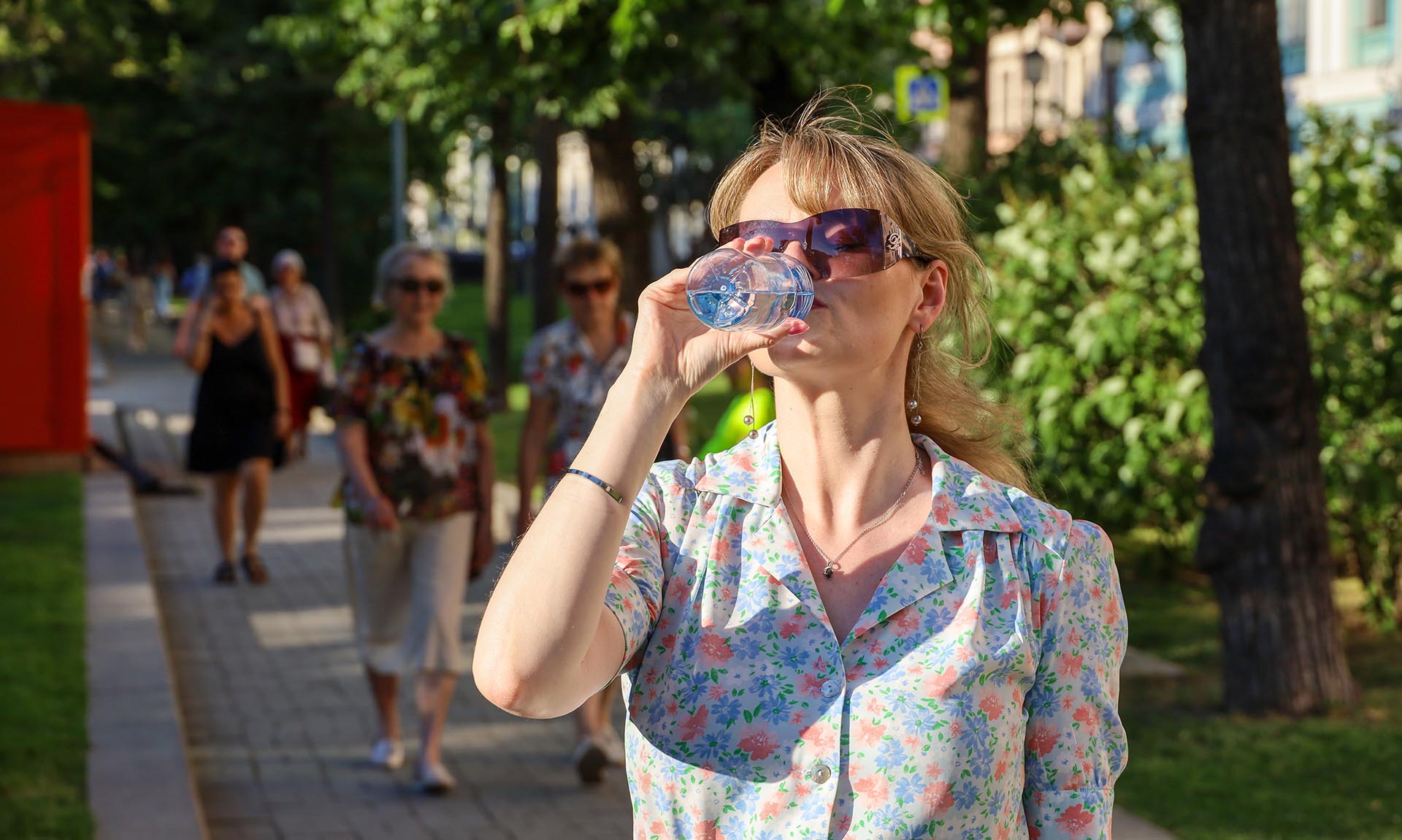 Девушка на улице пьет воду 