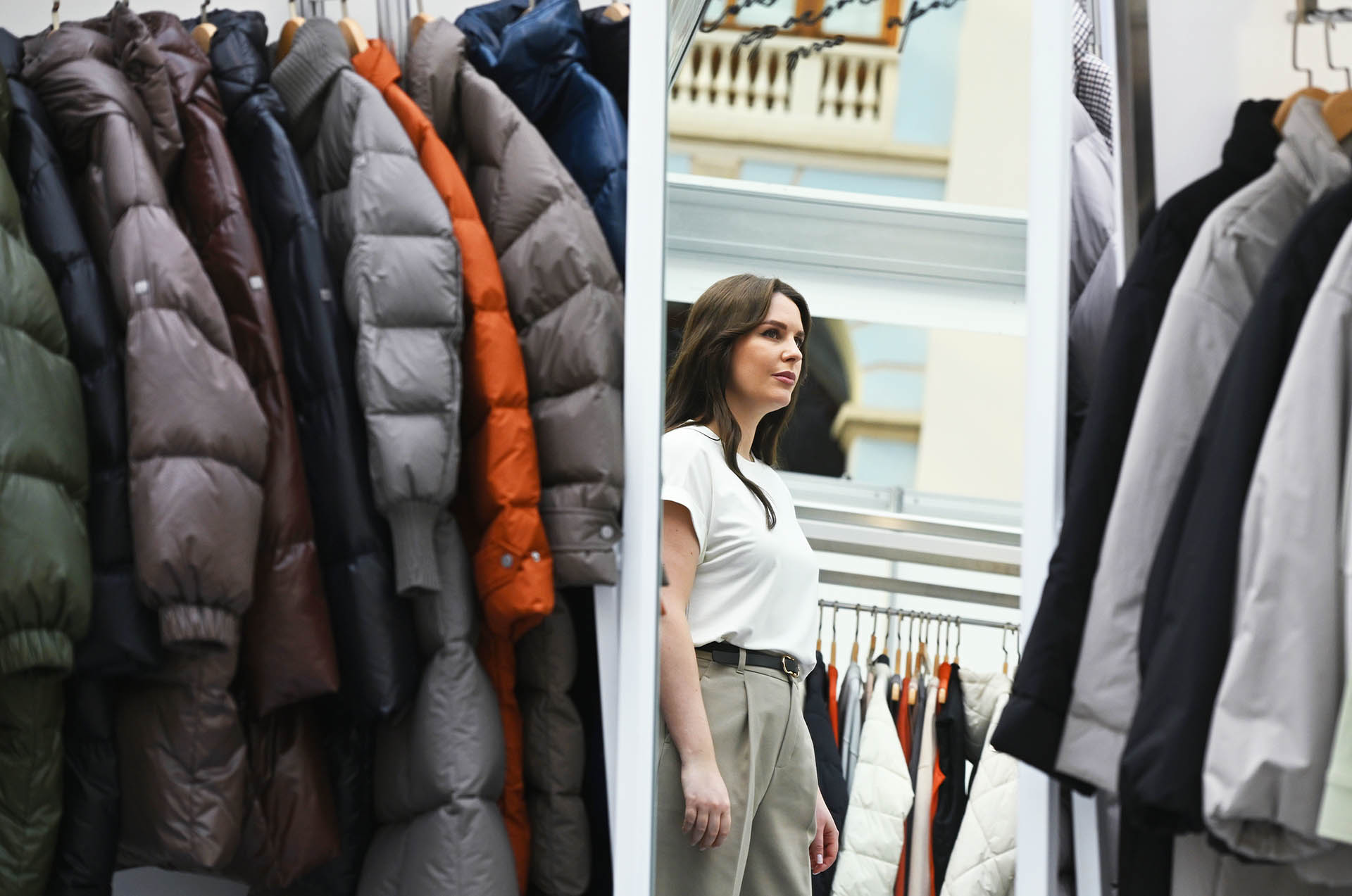 девушка смотрит в зеркало в бутике одежды