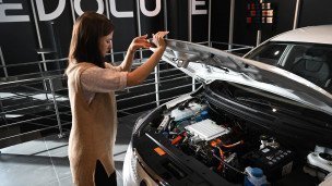 Девушка проверяет капот электроседана Evolute
