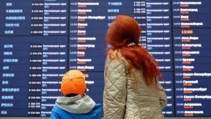  Женщина с ребенком у информационного табло международного терминала 