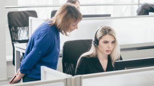 Сотрудница офиса за компьютером рядом стоит её начальница