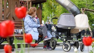 Женщина с коляской на детской площадке
