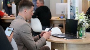 Мужчина с телефоном и планшетом сидит за ноутбуком