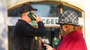 Мужчина и женщина с телефоном около отделения Сбера
