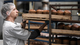 Сотрудник снимает со стеллажа поднос