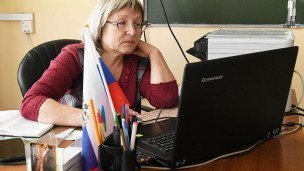 Школьный педагог сидит за ноутбуком