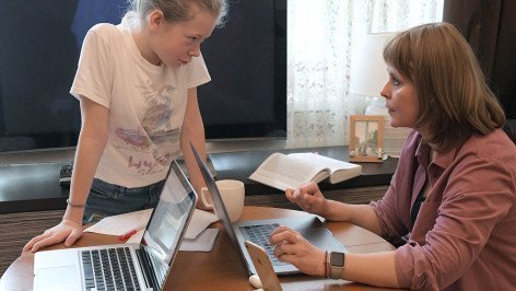 Женщина за ноутбуком рядом ее дочь