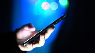 Мужчина держит в руках мобильный телефон