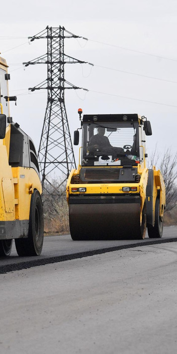 Сотрудники дорожно-строительной компании ремонтируют участок дороги