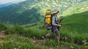 Туристка с рюкзаком в горах на Кавказе