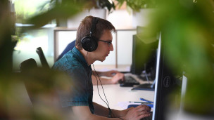 Сотрудник в офисе за компьютером в наушниках