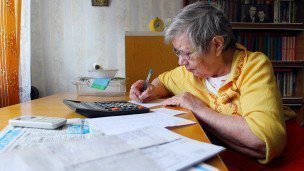 Пенсионерка проверяет счета за коммунальные услуг