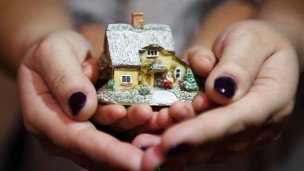 Женщина с ребенком держат макет дома