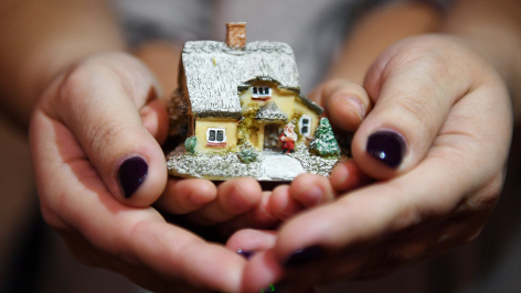 Женщина с ребенком держат макет дома