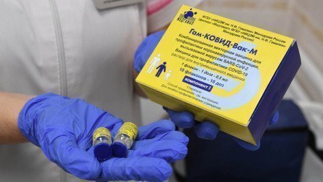 Медицинская сестра держит в руках упаковку ампул с вакциной "Гам-КОВИД-Вак-М" ("Спутник М") в прививочном кабинете детской поликлиники