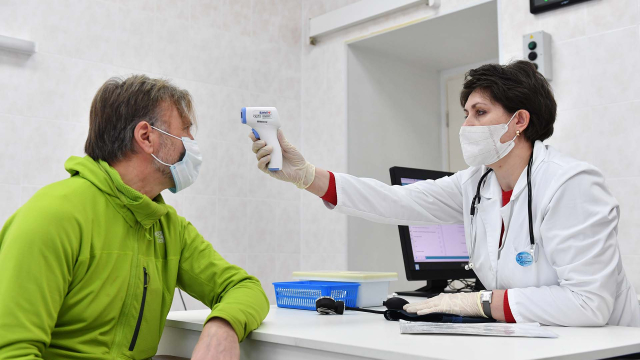 Врач измеряет температуру мужчине