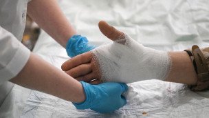 Сотрудница медицинского отряда специального назначения перевязывает руку раненому бойцу