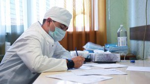 Врач за письменным столом заполняет документы