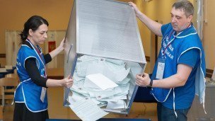 Сотрудники участковой избирательной комиссии достают избирательные бюллетени