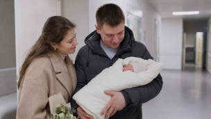 Супружеская пара на выписки из роддома с ребенком на руках