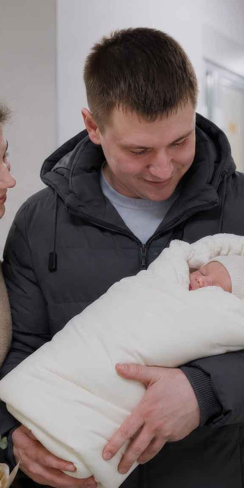 Супружеская пара на выписки из роддома с ребенком на руках