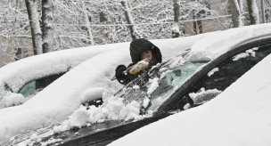 Женщина очищает машину от снега