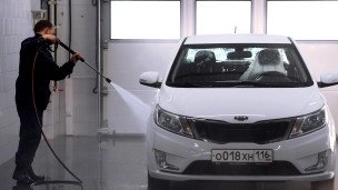 Сотрудник автомойки моет автомобиль 