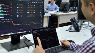 мужчина перед компьютером смотрит на графики  на двух мониторах