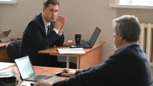 Студент с ноутбуком сидит напротив профессора 