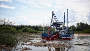 Бригада рабочих с помощью земснаряда очищает водоем от донных отложений и зарослей