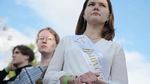 крупный план Выпускница со светлыми волосами до плеч сзади стоят её одноклассники  