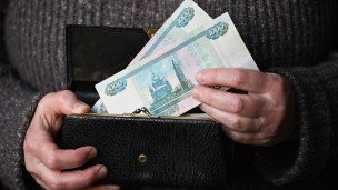 Женщина держит кошелек с тысячными рублевыми купюрами