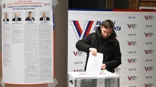 Мужчина голосует на выборах президента России на избирательном участке