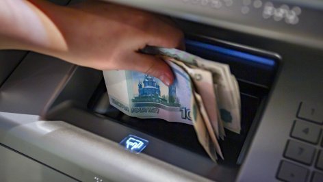 Посетитель достает деньги из банкомата