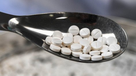 Круглые таблетки на мерной ложечке крупный план