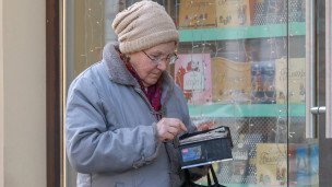 Женщина с кошельком на фоне витрины магазина