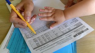 Женщина заполняет квитанции на оплату коммунальных услуг
