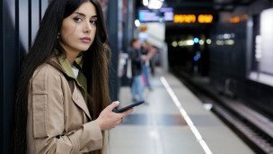 Девушка на платформе станции метро с телефоном в руках