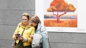две женщины на выставке на фоне картины