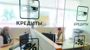 Менеджеры в офисе банка на стеклянной перегородке надпись "Кредиты"