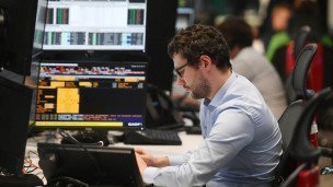 Мужчина за компьютером вокруг него экраны с уровнем валют