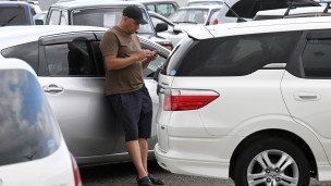 Мужчина возле выставленных на продажу подержанных легковых автомобилей