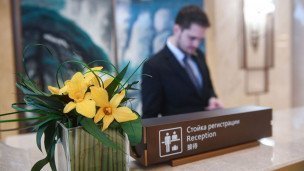 Ресепшн отеля крупным планом табличка Стойка регистрации и цветы в вазе на заднем плане работник отеля 
