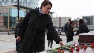 Женщина возлагает цветы на площади во время акции в память о жертвах теракта в подмосковном "Крокус Сити Холле"