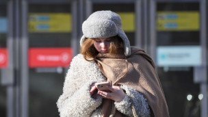 Девушка в теплой одежде на улице с телефоном