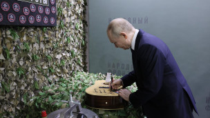 Владимир Путин оставляет памятную надпись на гитаре 