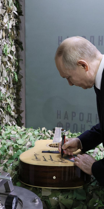 Владимир Путин оставляет памятную надпись на гитаре 